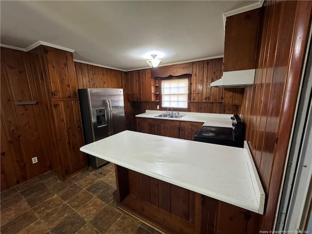 kitchen featuring sink, black electric range oven, kitchen peninsula, stainless steel fridge, and wood walls