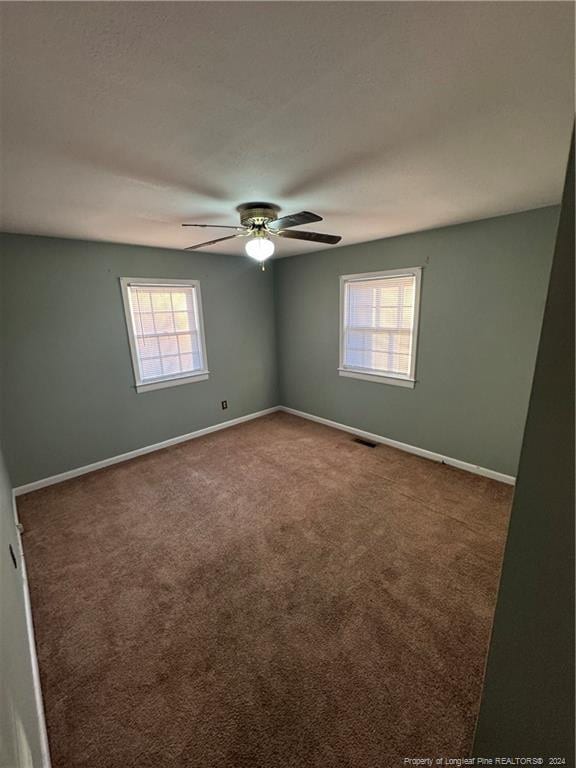 carpeted spare room featuring ceiling fan and a healthy amount of sunlight