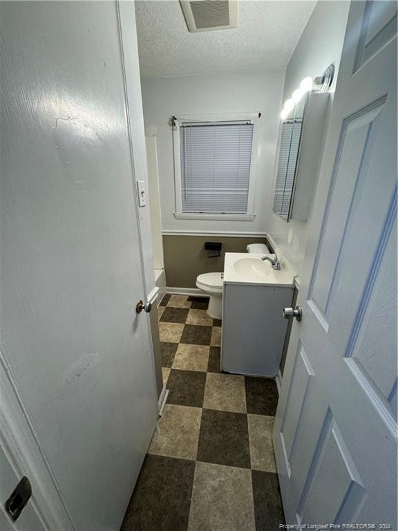 bathroom featuring a textured ceiling, vanity, and toilet