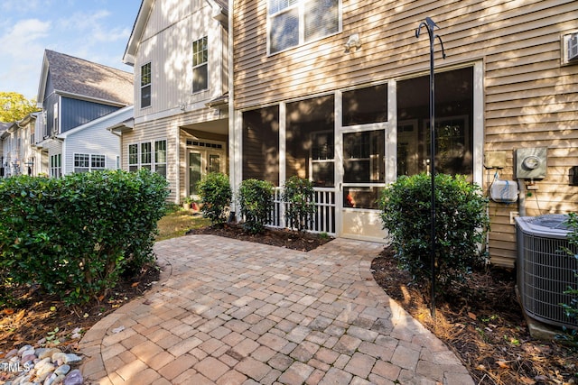 view of patio with central air condition unit and a sunroom