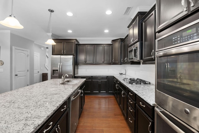 kitchen featuring appliances with stainless steel finishes, tasteful backsplash, ornamental molding, pendant lighting, and sink