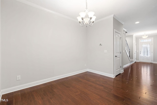 spare room featuring dark wood-type flooring, crown molding, and a chandelier