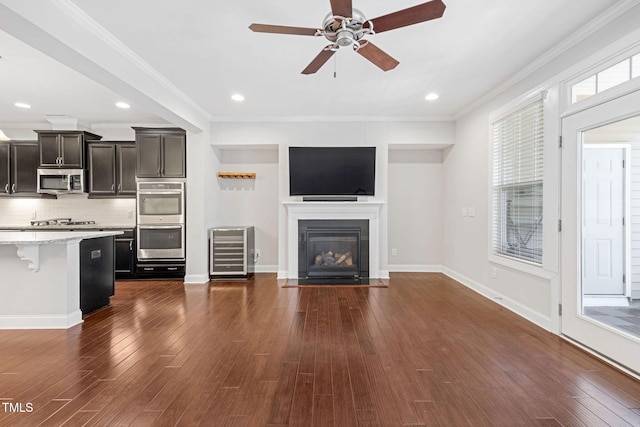 unfurnished living room featuring ceiling fan, crown molding, wine cooler, and dark hardwood / wood-style floors