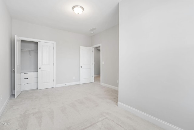 unfurnished bedroom with light colored carpet and a closet