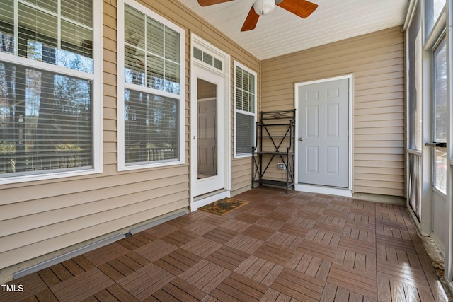 unfurnished sunroom featuring ceiling fan and plenty of natural light