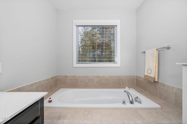 bathroom with tiled tub and vanity