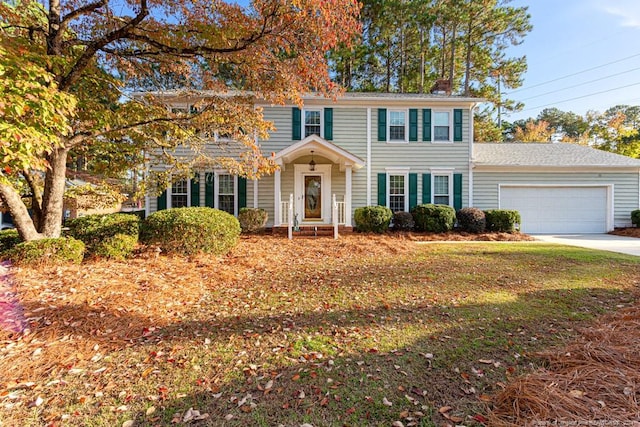 colonial inspired home with a garage and a front lawn