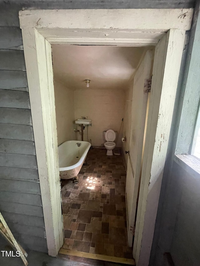 bathroom with a washtub, toilet, and sink