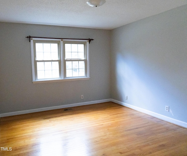 spare room featuring light wood-type flooring and a textured ceiling