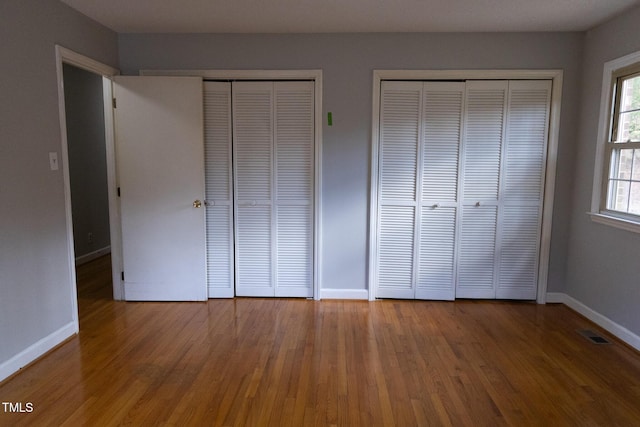 unfurnished bedroom featuring multiple closets and hardwood / wood-style floors