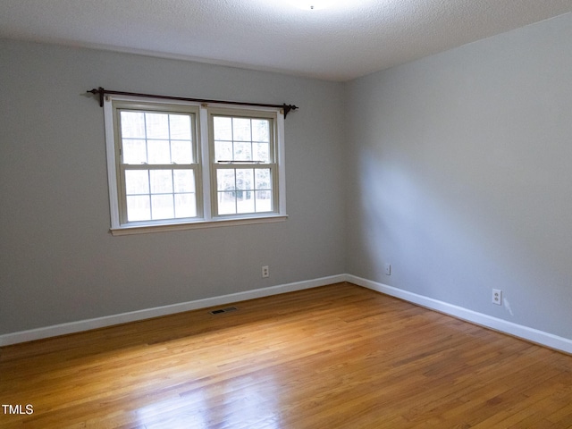 spare room featuring a textured ceiling and light hardwood / wood-style flooring