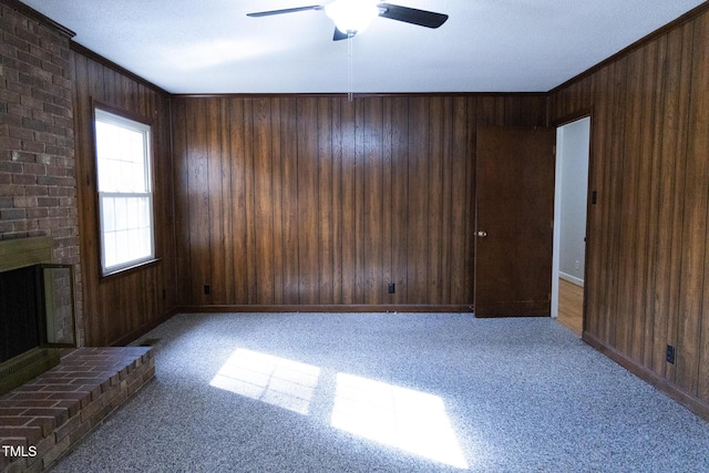 unfurnished living room featuring ceiling fan, a fireplace, light carpet, and wooden walls