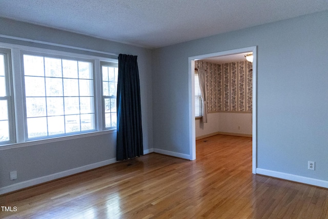 unfurnished room featuring light hardwood / wood-style floors and a textured ceiling