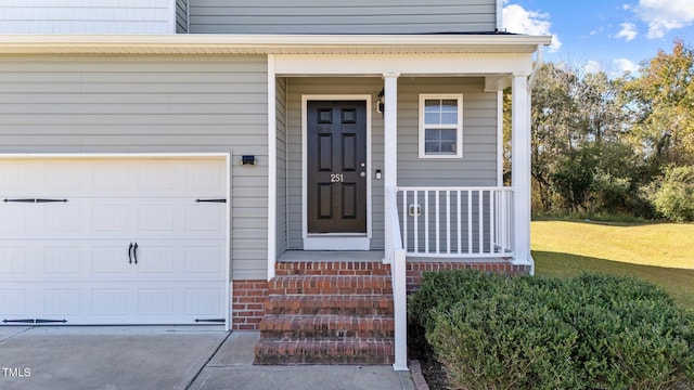 entrance to property featuring a yard, a porch, and a garage