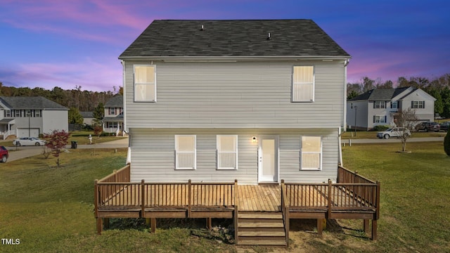 back house at dusk with a yard and a wooden deck