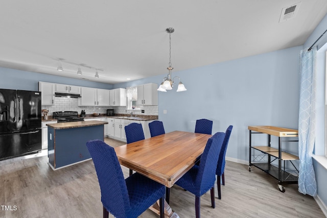 dining area featuring a chandelier, light hardwood / wood-style flooring, and sink