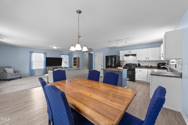 dining space featuring a chandelier, light wood-type flooring, and sink