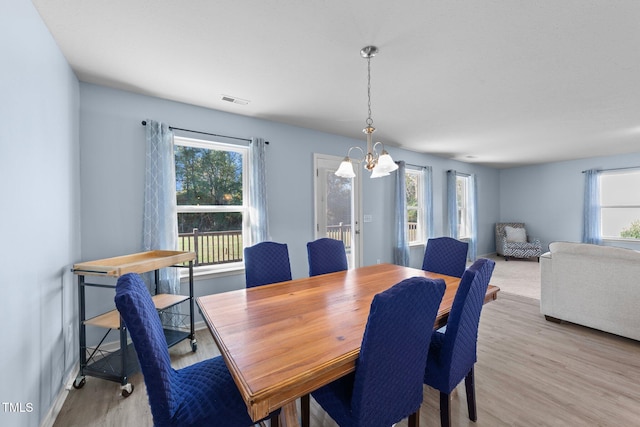 dining space featuring light hardwood / wood-style flooring, a wealth of natural light, and a notable chandelier