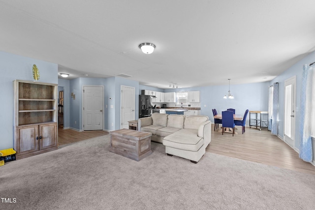 living room featuring light wood-type flooring and an inviting chandelier