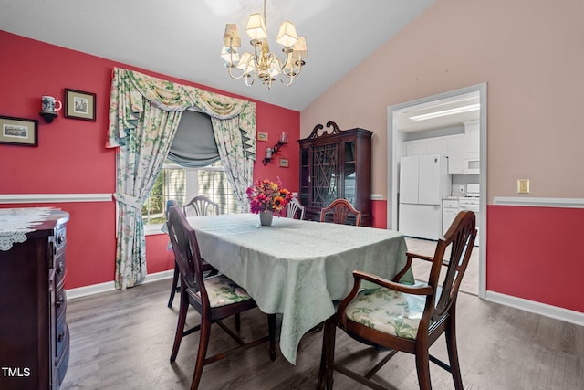 dining space featuring a chandelier, hardwood / wood-style flooring, and vaulted ceiling