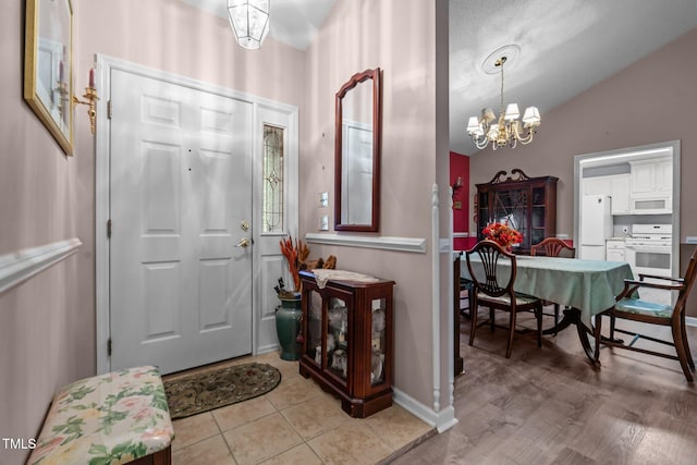 tiled entrance foyer with lofted ceiling and a notable chandelier