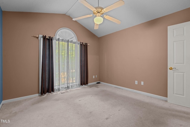 empty room with ceiling fan, light colored carpet, and vaulted ceiling