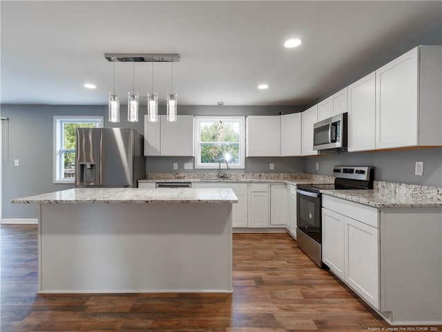 kitchen featuring a center island, stainless steel appliances, white cabinetry, and plenty of natural light