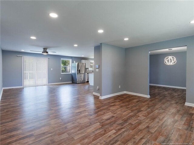 unfurnished living room featuring dark hardwood / wood-style flooring and ceiling fan with notable chandelier