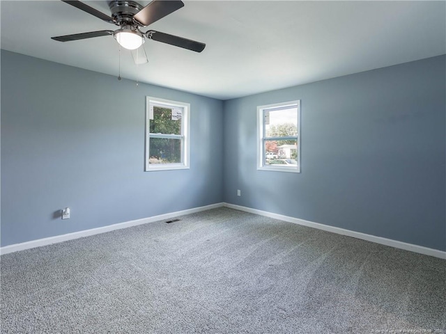 carpeted spare room featuring ceiling fan and plenty of natural light