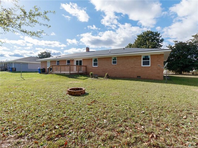 back of house with a yard, a fire pit, and a deck