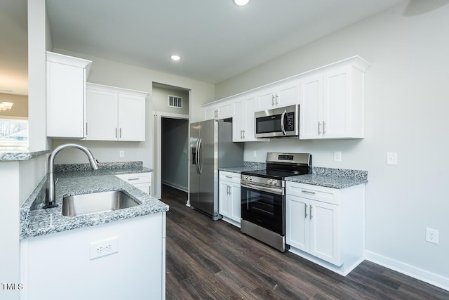 kitchen featuring stainless steel appliances, visible vents, white cabinets, a sink, and light stone countertops