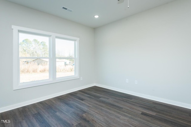 unfurnished room with baseboards, visible vents, dark wood-style flooring, and recessed lighting