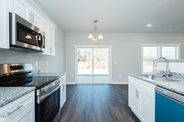 kitchen with light stone counters, a sink, white cabinets, appliances with stainless steel finishes, and dark wood-style floors