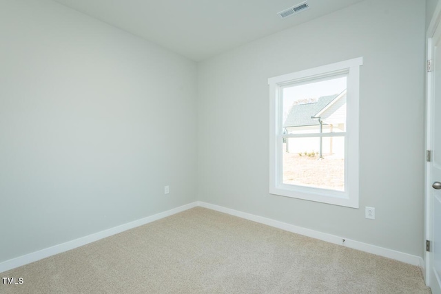 spare room with baseboards, visible vents, and light colored carpet