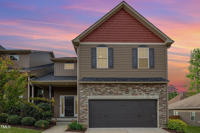 view of front of property with a garage, roof with shingles, stone siding, and concrete driveway