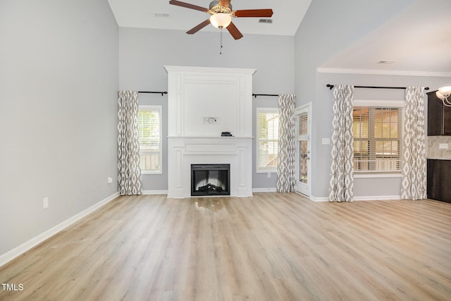 unfurnished living room featuring light wood finished floors, baseboards, high vaulted ceiling, ceiling fan, and a fireplace