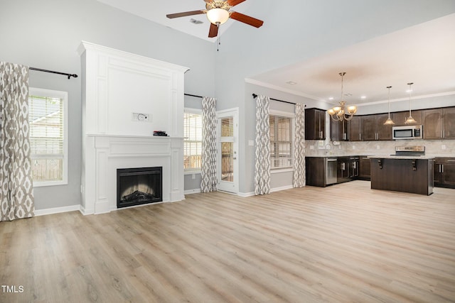 unfurnished living room with baseboards, light wood-style floors, ceiling fan with notable chandelier, crown molding, and a fireplace