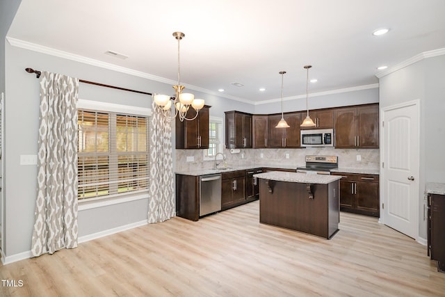 kitchen with light wood finished floors, stainless steel appliances, dark brown cabinets, decorative backsplash, and a kitchen island