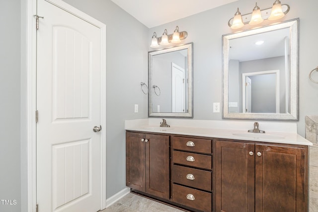 bathroom with double vanity, baseboards, and a sink