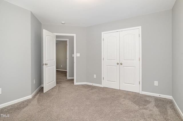 unfurnished bedroom featuring baseboards, carpet floors, and a closet