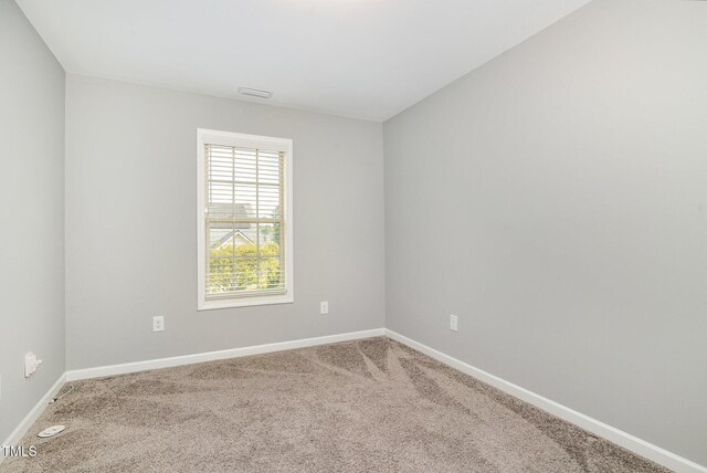 carpeted empty room featuring visible vents and baseboards
