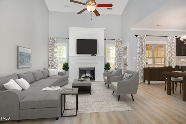 living area featuring high vaulted ceiling, a ceiling fan, light wood-style floors, and visible vents
