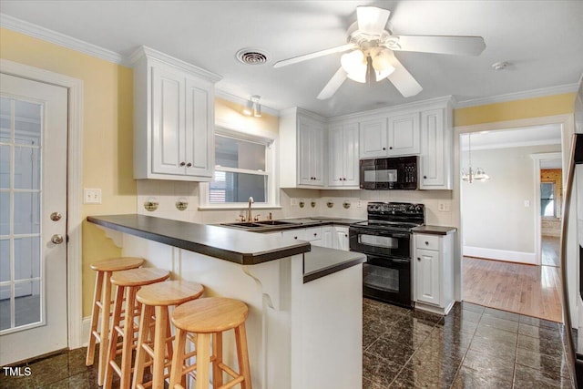 kitchen featuring a kitchen bar, kitchen peninsula, sink, black appliances, and white cabinetry