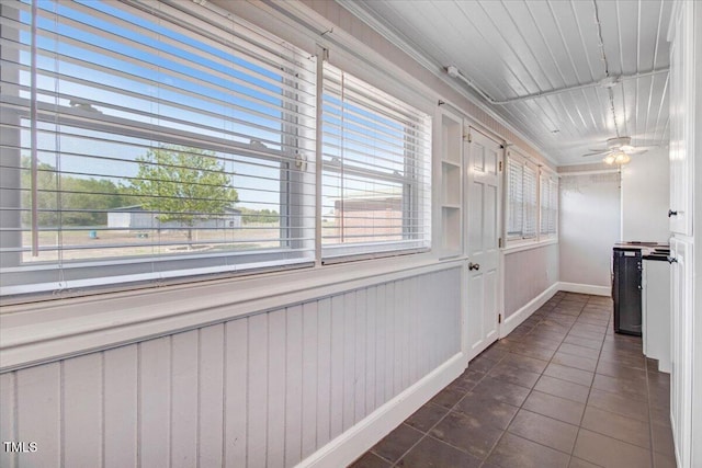 hallway with wooden walls, dark tile patterned flooring, and crown molding