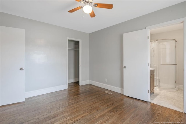 unfurnished bedroom with ensuite bath, ceiling fan, a closet, and dark wood-type flooring