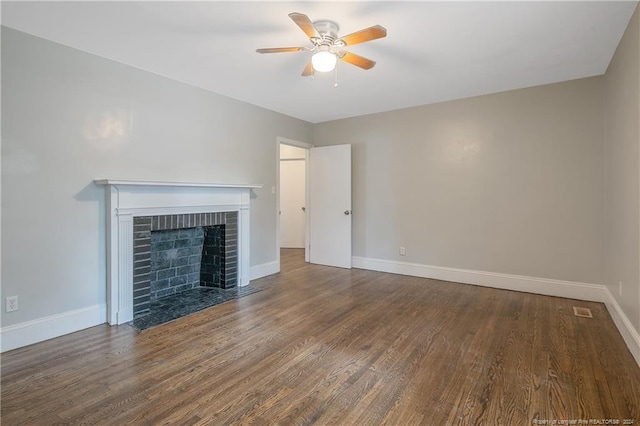 unfurnished living room featuring dark hardwood / wood-style flooring, a brick fireplace, and ceiling fan