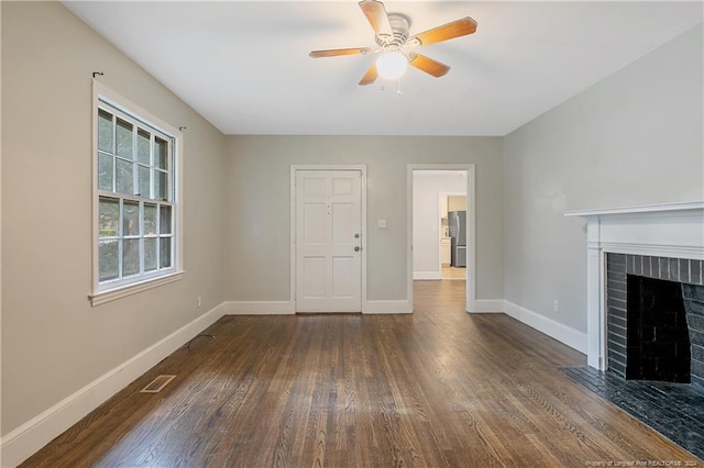 unfurnished living room featuring ceiling fan, dark wood-type flooring, and a brick fireplace