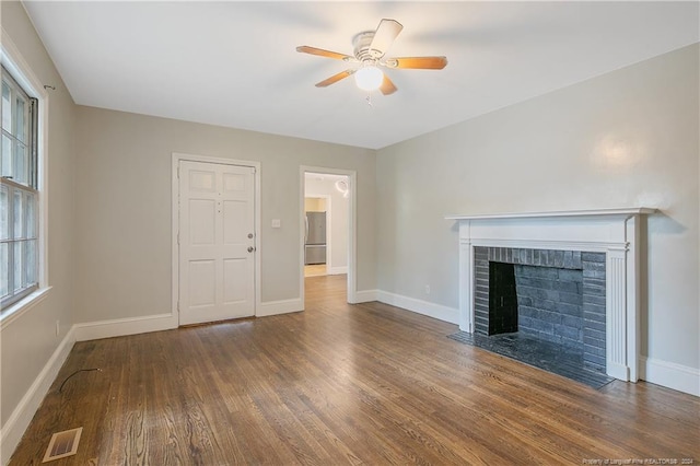 unfurnished living room with dark hardwood / wood-style flooring, a brick fireplace, and ceiling fan