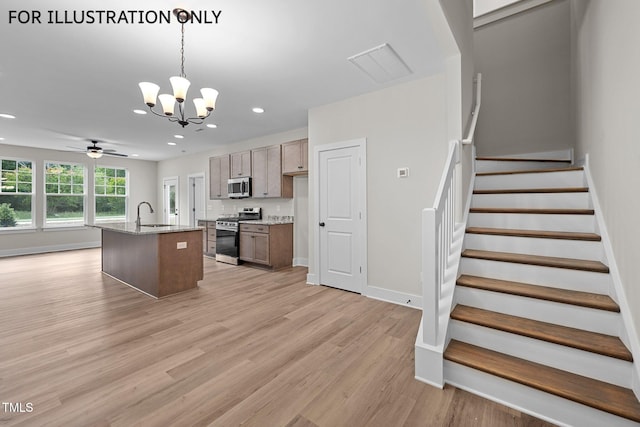 kitchen featuring ceiling fan with notable chandelier, light hardwood / wood-style flooring, an island with sink, appliances with stainless steel finishes, and decorative light fixtures