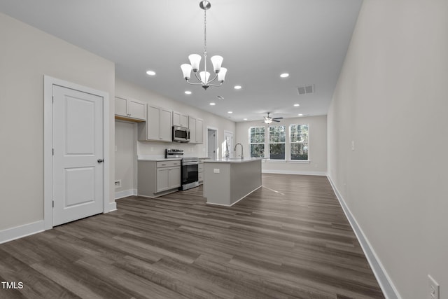 kitchen with sink, hanging light fixtures, stainless steel appliances, dark hardwood / wood-style floors, and an island with sink